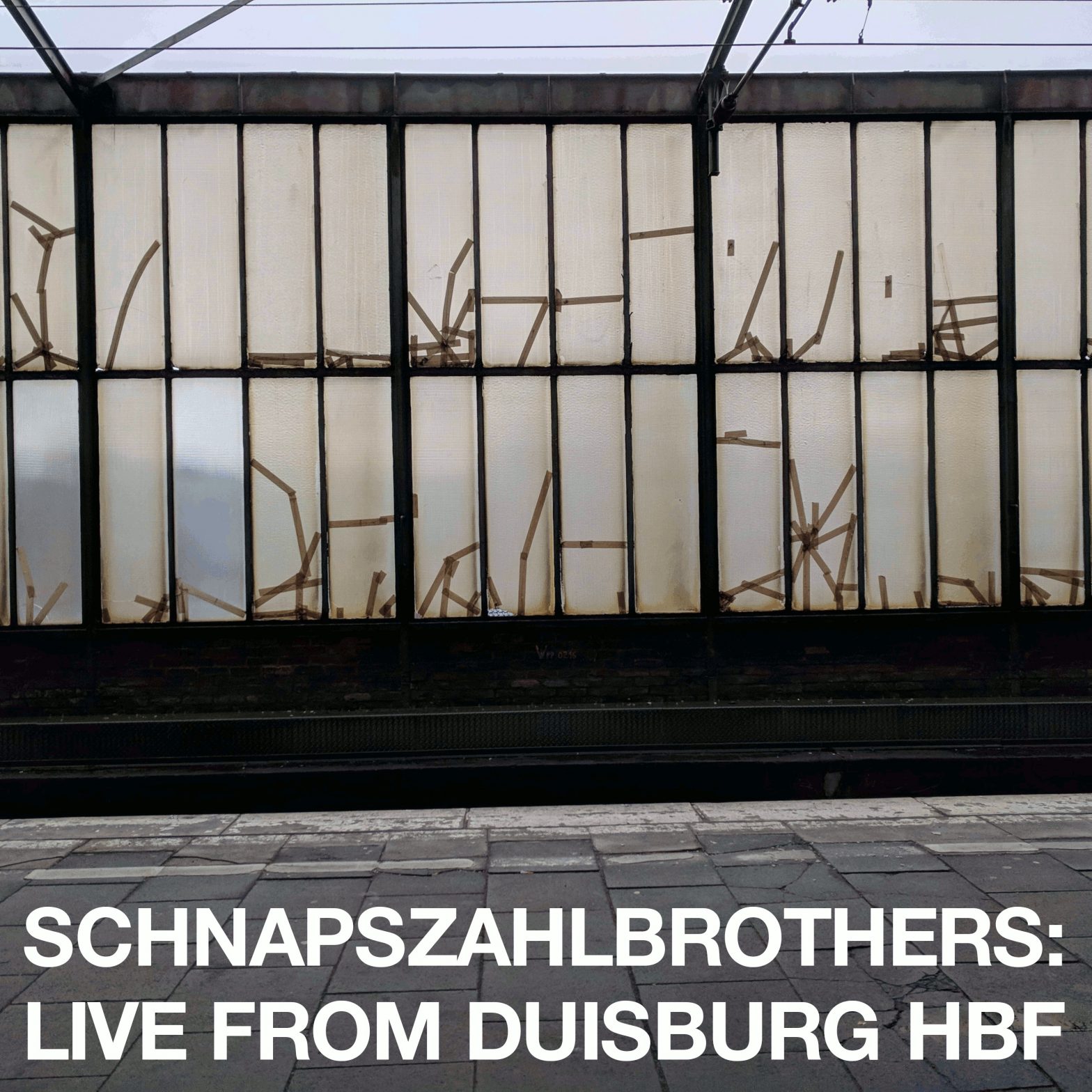 Eine schmutzige Bahnhofshallenwand. Aufschrift: Schnapszahlbrothers: Live from Duisburg Hbf